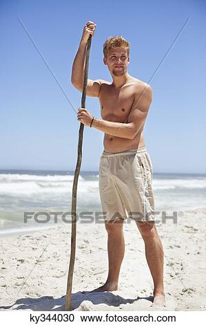 Man standing on the beach with a stick View Large Photo Image Stock Image - Man standing on the beach with a stick. Fotosearch