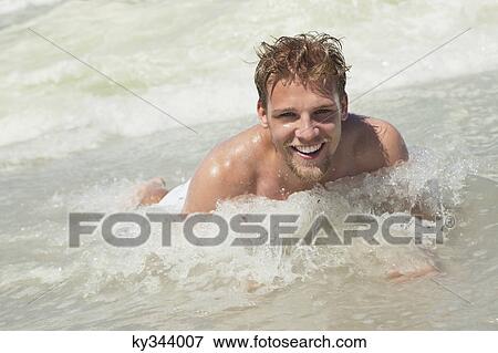 Stock Photo - Portrait of a young man lying in water. Fotosearch
