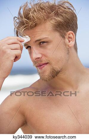 Young man applying moisturizer on his face View Large Photo Image Stock Photo - Young man applying moisturizer on his face. Fotosearch