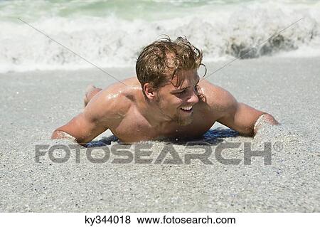 Young man lying on sand View Large Photo Image Stock Photo - Young man lying on sand. Fotosearch