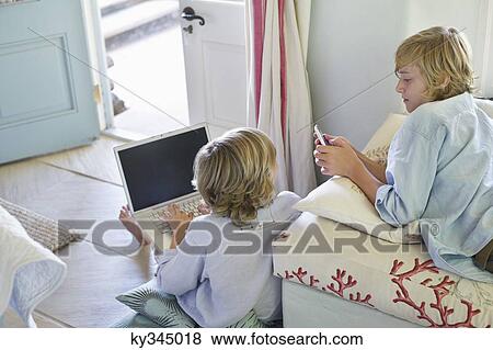 Children using electronic gadgets at home View Large Photo Image Stock Photo - Children using electronic gadgets at home. Fotosearch