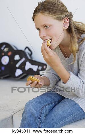 Stock Image - Close-up of a girl eating cookies and smiling. Fotosearch