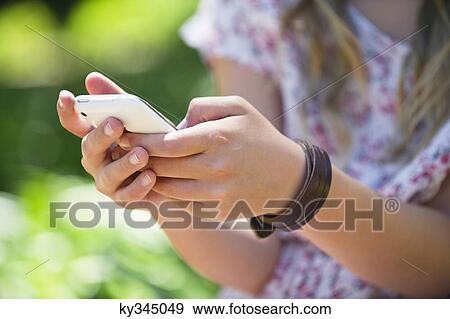 Close-up of a little girl using a mobile phone outdoors View Large Photo Image Stock Photo - Close-up of a little girl using a mobile phone outdoors. Fotosearch
