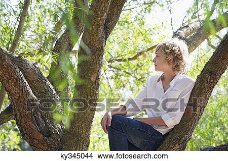 Contemplative little boy sitting on tree branch View Large Photo Image Picture - Contemplative little boy sitting on tree branch. Fotosearch
