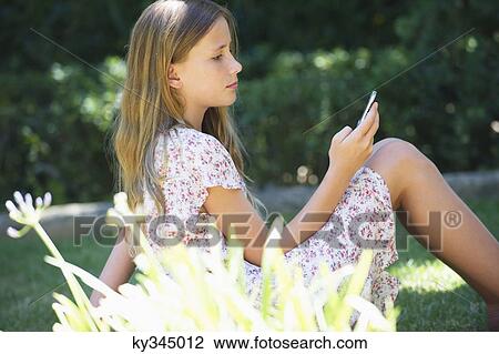 Cute little girl using a mobile phone outdoors View Large Photo Image Stock Image - Cute little girl using a mobile phone outdoors. Fotosearch