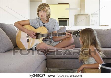 Girl looking at a her brother playing a guitar View Large Photo Image Stock Photo - Girl looking at a her brother playing a guitar. Fotosearch