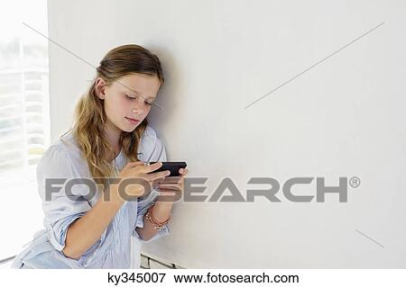 Stock Photo - Girl playing with a handheld video game at home. Fotosearch