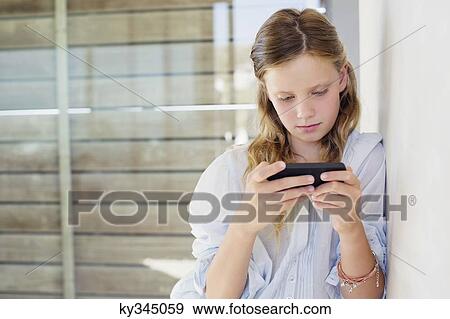 Girl playing with a handheld video game at home View Large Photo Image Stock Photo - Girl playing with a handheld video game at home. Fotosearch