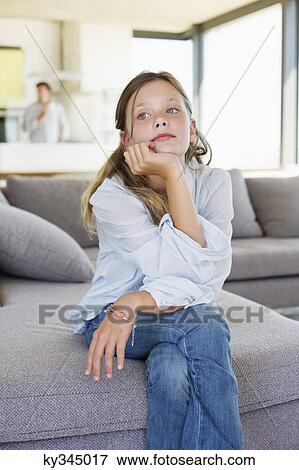 Stock Photo - Girl sitting on a couch and thinking. Fotosearch
