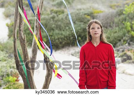 Girl standing near a decorated tree View Large Photo Image Stock Photograph - Girl standing near a decorated tree. Fotosearch