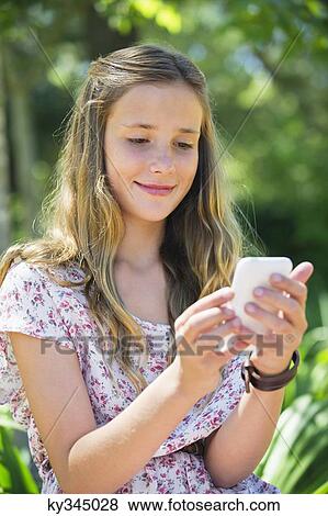 Smiling little girl text messaging using a mobile phone View Large Photo Image Stock Photo - Smiling little girl text messaging using a mobile phone. Fotosearch