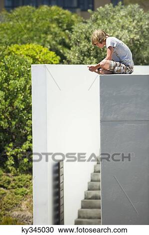 Teenage boy sitting at the edge of a terrace View Large Photo Image Stock Image - Teenage boy sitting at the edge of a terrace. Fotosearch