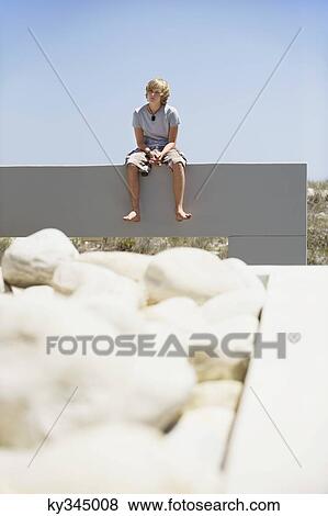 Teenage boy sitting at the edge of a terrace View Large Photo Image Stock Photo - Teenage boy sitting at the edge of a terrace. Fotosearch