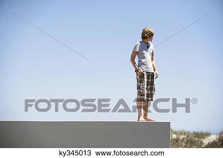 Stock Image - Teenage boy standing at the edge of a terrace. Fotosearch