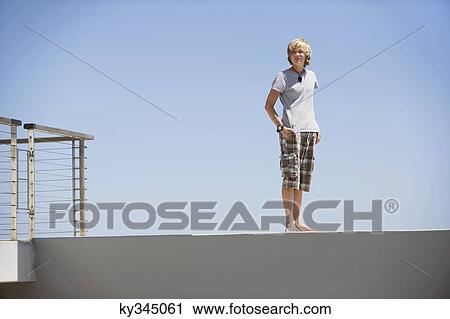 Stock Image - Teenage boy standing at the edge of a terrace. Fotosearch