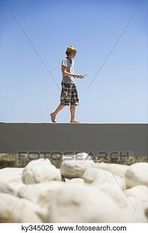 Teenage boy walking on the edge of a terrace View Large Photo Image Stock Photograph - Teenage boy walking on the edge of a terrace. Fotosearch