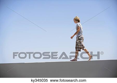 Teenage boy walking on the edge of a terrace View Large Photo Image Stock Photography - Teenage boy walking on the edge of a terrace. Fotosearch