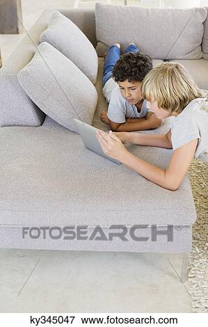 Teenage boy with his brother looking at a digital tablet View Large Photo Image Stock Photo - Teenage boy with his brother looking at a digital tablet. Fotosearch
