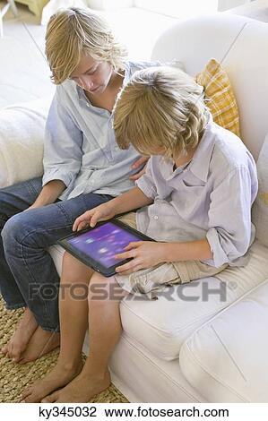 Stock Image - Two little boys using digital tablet at house. Fotosearch