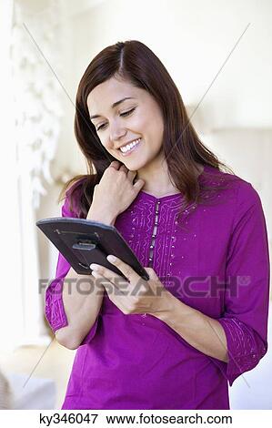 Beautiful young woman looking at photo frame and smiling View Large Photo Image Stock Photo - Beautiful young woman looking at photo frame and smiling. Fotosearch