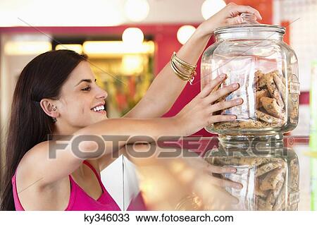 Smiling woman holding a jar of cookies in a bakery View Large Photo Image Stock Image - Smiling woman holding a jar of cookies in a bakery. Fotosearch
