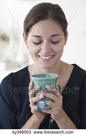 Smiling young woman drinking hot tea at home View Large Photo Image Stock Image - Smiling young woman drinking hot tea at home. Fotosearch