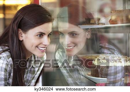 Woman looking at cakes in a bakery window View Large Photo Image Picture - Woman looking at cakes in a bakery window. Fotosearch