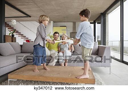 Boys playing with their parents sitting on a couch View Large Photo Image Stock Image - Boys playing with their parents sitting on a couch. Fotosearch
