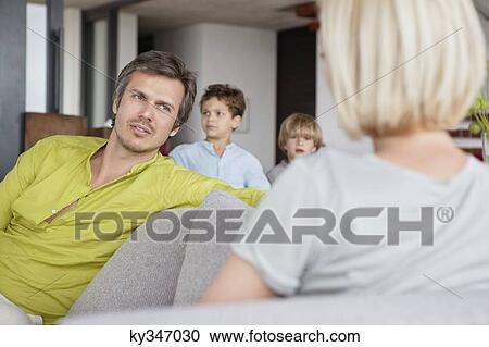 Couple having conversation while children standing in background View Large Photo Image Stock Image - Couple having conversation while children standing in background. Fotosearch