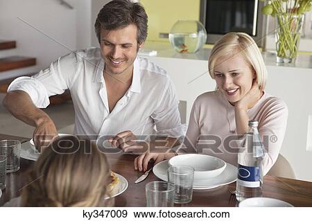 Stock Photo - Couple having food with their daughter. Fotosearch