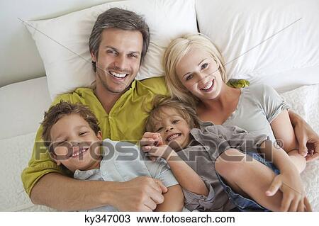 Couple with their children relaxing in bed View Large Photo Image Stock Image - Couple with their children relaxing in bed. Fotosearch