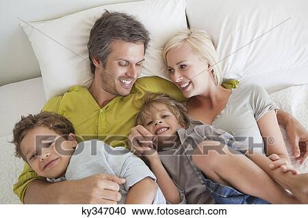 Couple with their children relaxing in bed View Large Photo Image Stock Image - Couple with their children relaxing in bed. Fotosearch