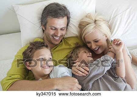 Couple with their children relaxing in bed View Large Photo Image Stock Photography - Couple with their children relaxing in bed. Fotosearch