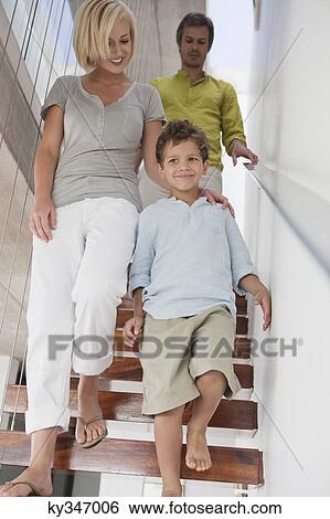 Stock Photograph - Couple with their son moving down from a staircase. Fotosearch