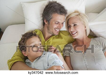 Parents with their son relaxing in bed View Large Photo Image Stock Image - Parents with their son relaxing in bed. Fotosearch