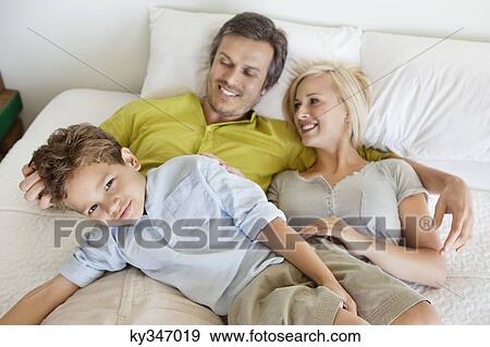 Stock Photo - Parents with their son relaxing in bed. Fotosearch
