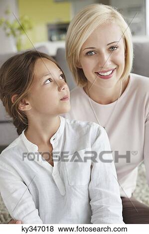 Portrait of a woman sitting with her daughter and smiling View Large Photo Image Stock Photo - Portrait of a woman sitting with her daughter and smiling. Fotosearch