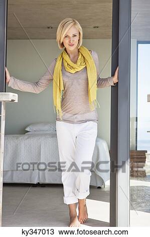 Stock Image - Portrait of a woman standing at the door. Fotosearch
