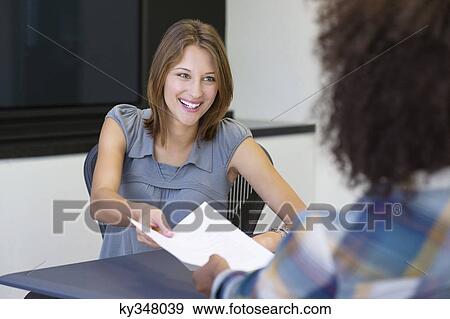 Stock Photo - African American woman giving resume to a businesswoman in office. Fotosearch