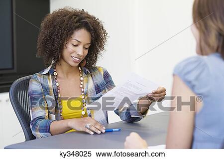 African American woman reading a resume while taking interview of a Caucasian woman View Large Photo Image Stock Photography - African American woman reading a resume while taking interview of a Caucasian woman. Fotosearch