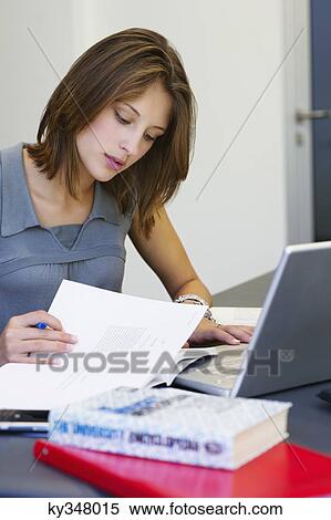 Beautiful woman reading a book while using laptop in classroom View Large Photo Image Stock Photography - Beautiful woman reading a book while using laptop in classroom. Fotosearch