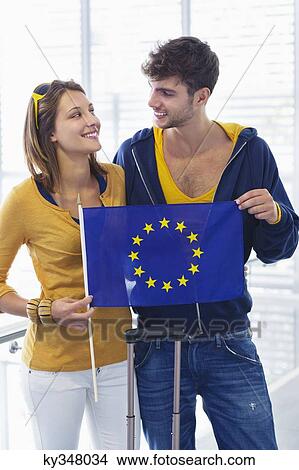 Couple holding European union flag at an airport and looking at each other View Large Photo Image Picture - Couple holding European union flag at an airport and looking at each other. Fotosearch
