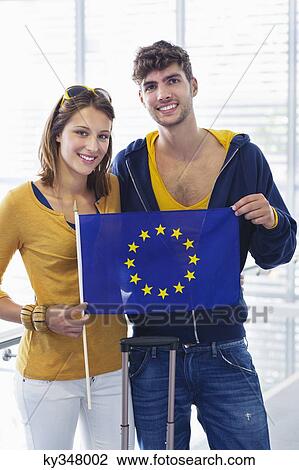 Portrait of a couple holding European union flag at an airport View Large Photo Image Stock Image - Portrait of a couple holding European union flag at an airport. Fotosearch