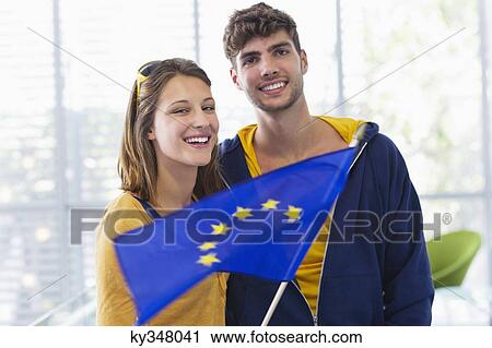 Portrait of a couple holding European union flag at an airport View Large Photo Image Stock Image - Portrait of a couple holding European union flag at an airport. Fotosearch