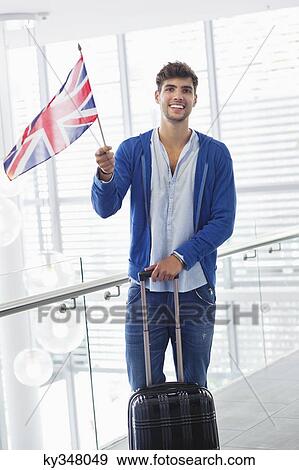 Portrait of a man holding British flag and a suitcase at an airport View Large Photo Image Stock Photo - Portrait of a man holding British flag and a suitcase at an airport. Fotosearch