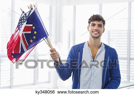 Portrait of a man holding flags of various countries at an airport View Large Photo Image Stock Photograph - Portrait of a man holding flags of various countries at an airport. Fotosearch