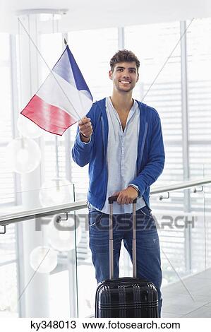 Portrait of a man holding French flag and a suitcase at an airport View Large Photo Image Stock Image - Portrait of a man holding French flag and a suitcase at an airport. Fotosearch