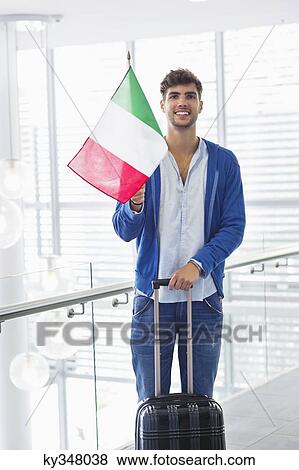 Portrait of a man holding Italian flag and a suitcase at an airport View Large Photo Image Stock Photo - Portrait of a man holding Italian flag and a suitcase at an airport. Fotosearch