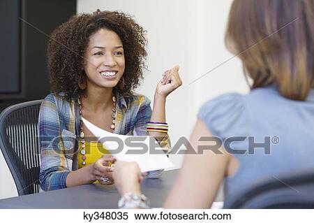 Rear view of a woman giving resume to an African American woman in office View Large Photo Image Stock Photography - Rear view of a woman giving resume to an African American woman in office. Fotosearch