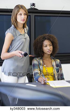 Two female university students giving presentation in a classroom View Large Photo Image Stock Image - Two female university students giving presentation in a classroom. Fotosearch